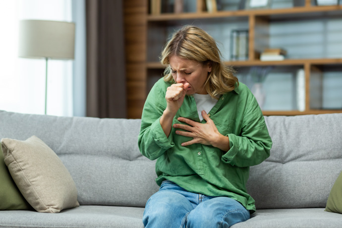 Mujer tosiendo por no saber cómo limpiar los pulmones de tabaco.