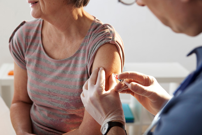 Médico enseñando a una persona cómo prevenir la gripe con vacunas.