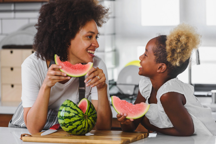 Mujer y niña comiendo sandía, una de las frutas aceptadas diabéticos.