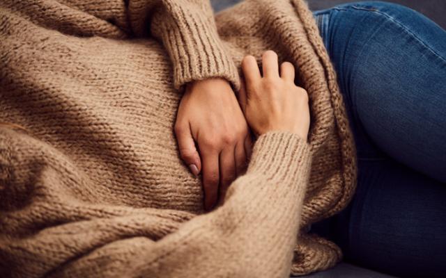 mujer tumbada con manos en la tripa