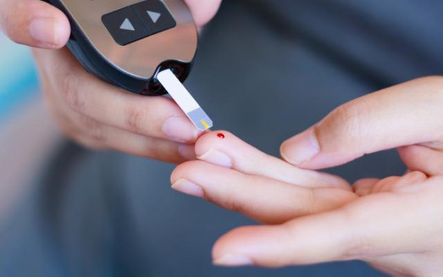 Persona midiendo sus niveles de glucosa con un glucómetro para identificar un posible pico de glucosa.