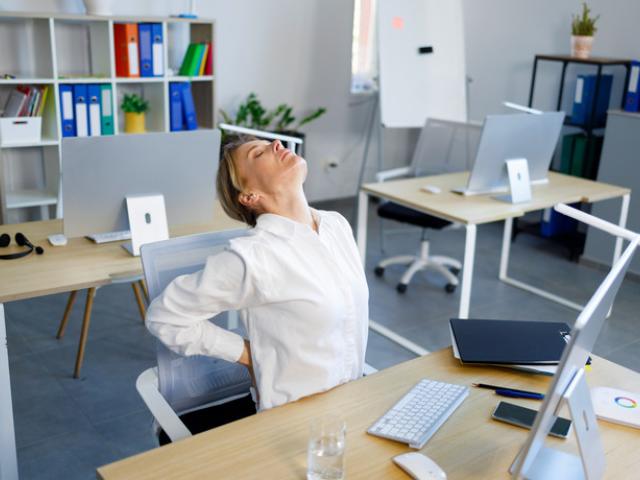 Mujer estirandose en su silla de trabajo 