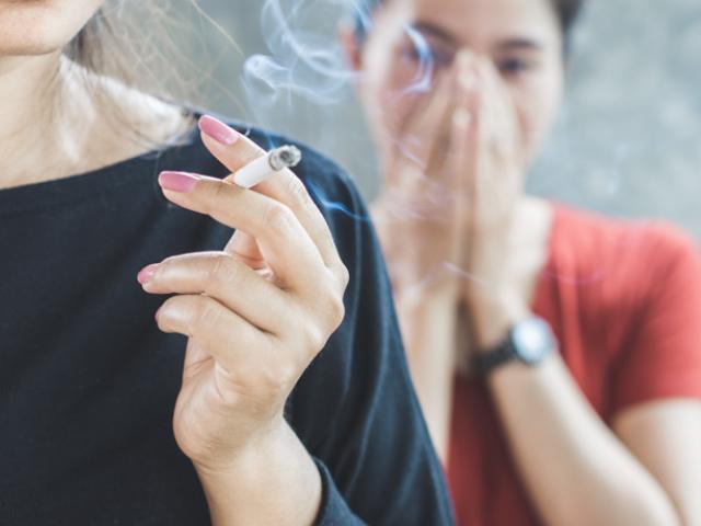 Ejemplo de fumadora pasiva evitando el humo del tabaco