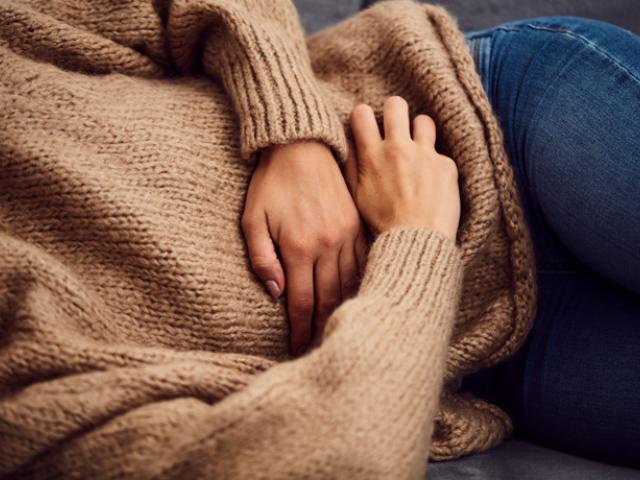 mujer tumbada con manos en la tripa