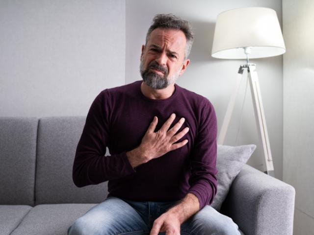 Hombre quejándose de dolor por no saber cómo bajar el colesterol de forma natural.