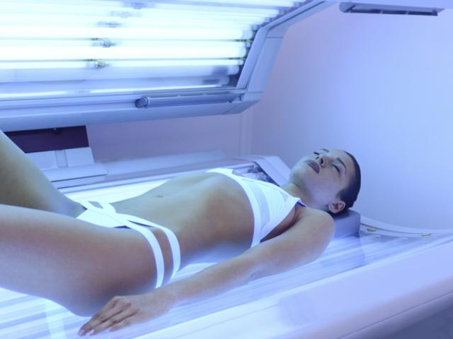 Mujer con adicción al sol en cama de bronceado